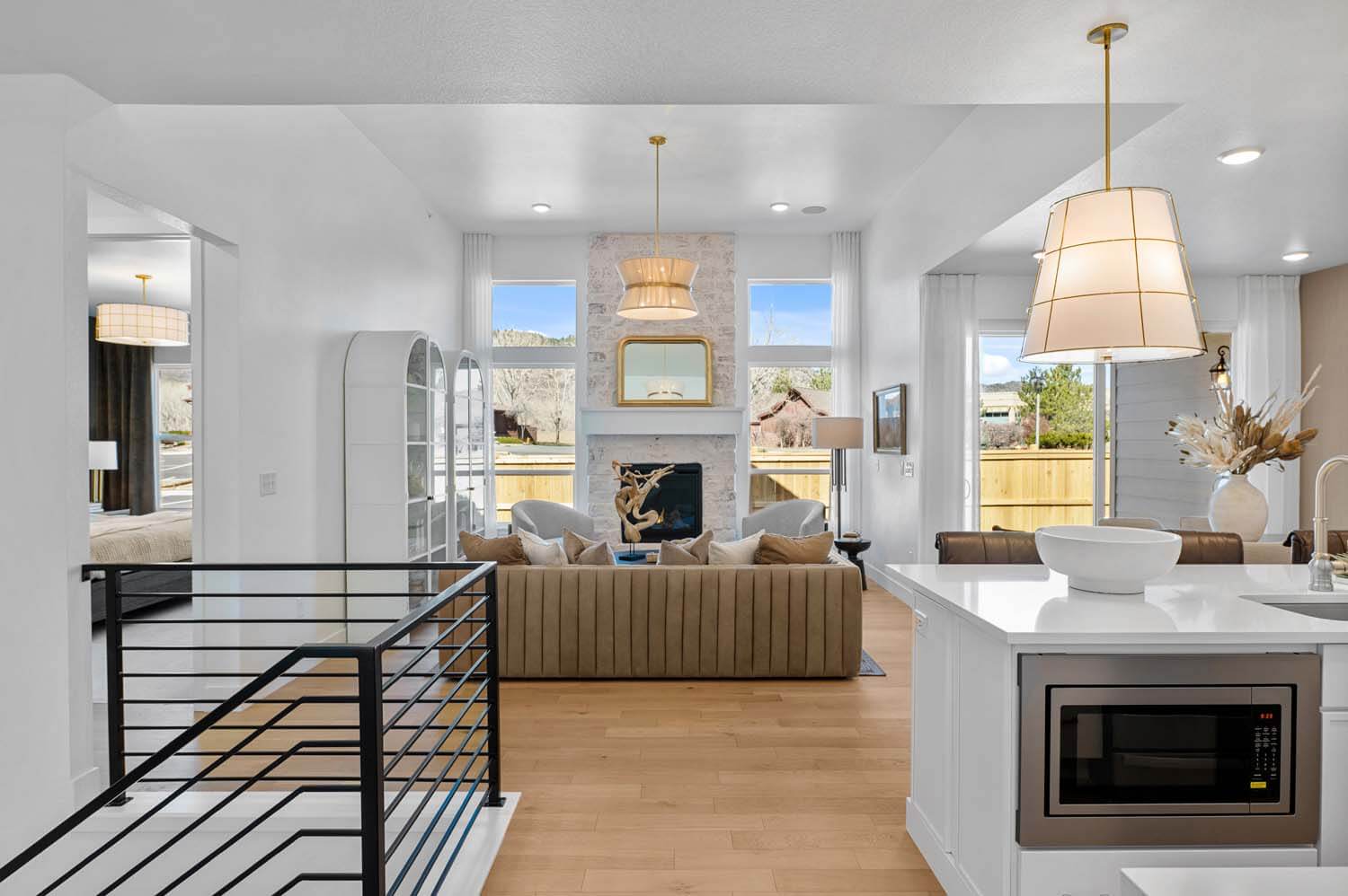 The open-concept floorplan has the kitchen next to the basement stairs and adjacent to the dining area and great room, which are at the back of the house. The door to the primary suite is off the great room. The space has hardwood floors, white walls and large windows.