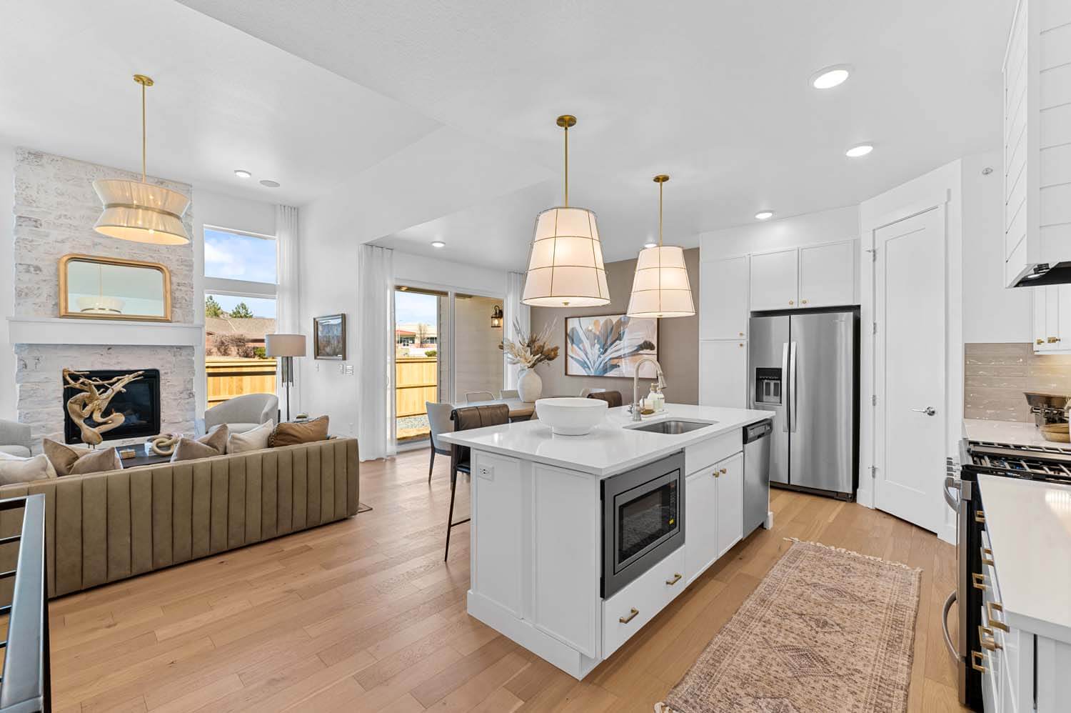 The open-concept floorplan has the kitchen facing the great room and the dining room. The rooms have white walls and light-colored wood floors.