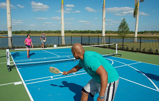 Four people playing pickleball on an outdoor court beside water