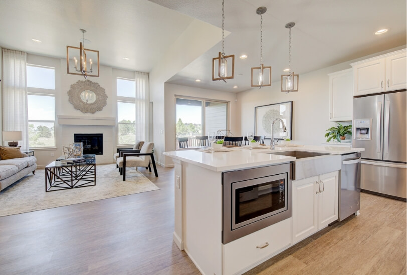 An open-concept floorplan with the kitchen facing the great room and the dining room. The rooms have white walls and light-colored wood floors.